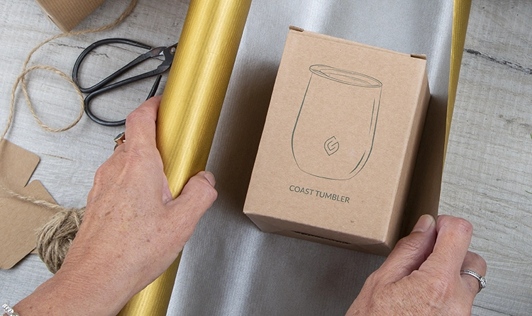 Hands wrapping a product with a gold wrapping paper |