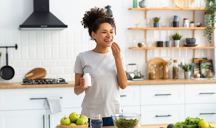 Smiling woman taking supplements in her kitchen 1 |