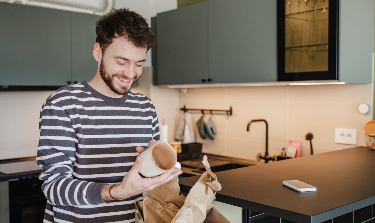 A man smiling while opening an online order of a mug.